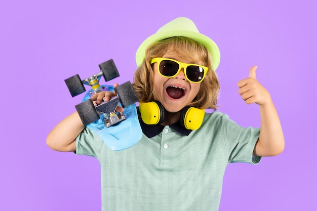 Excited child with thumb up child boy with skateboard over isolated background