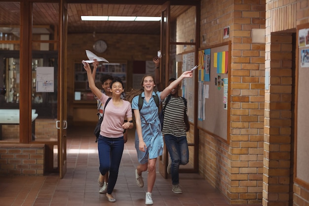 Excited classmates running with grade cards in corridor