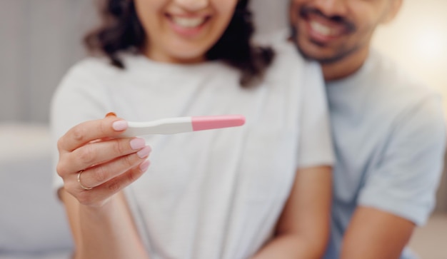 Excited couple hands and positive pregnancy test for maternity start or family at home Closeup of happy man and pregnant woman smile for parenthood morning or good news or results in bedroom