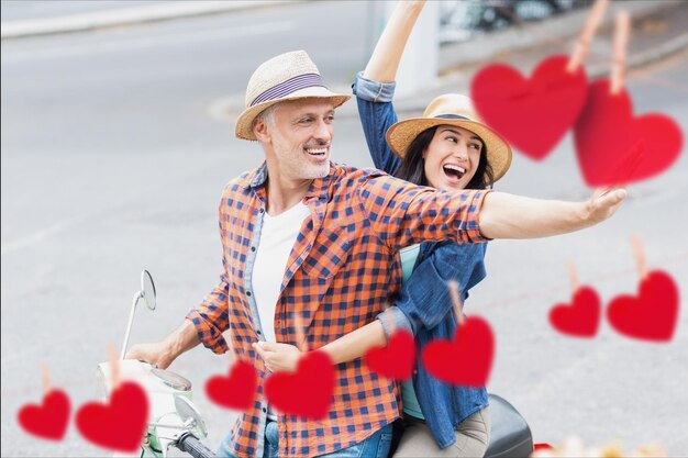 Excited couple waving hands while riding scooter