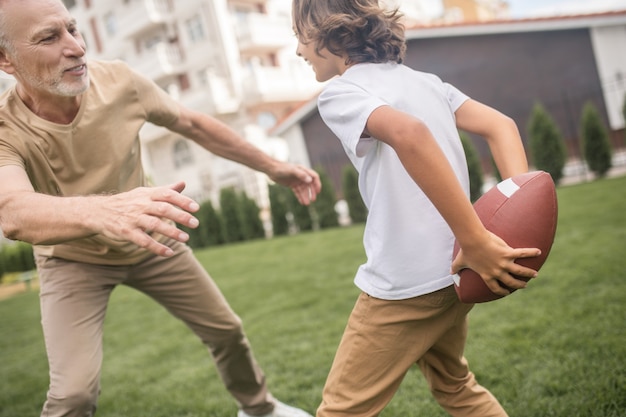 Excited. Dark-haired boy and his dad looking excited while playing ball