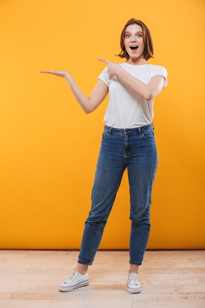 Excited emotional young woman showing copyspace.