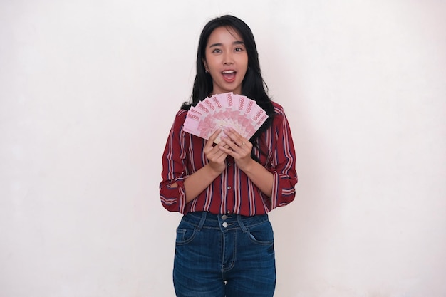 Excited expression of an Asian woman standing and holding some rupiah money for shopping