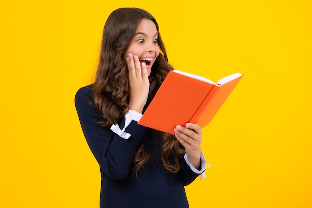 Excited face Back to school Teenager schoolgirl with book ready to learn School girl children on isolated yellow studio background Amazed expression cheerful and glad