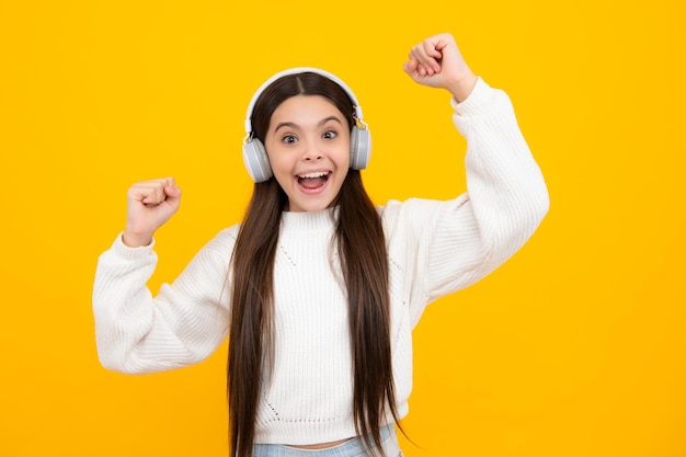 Excited face Child music concept Teenager child girl dances in rhythm of melody listens song in headphones Child listening to music through earphones Amazed expression cheerful and glad