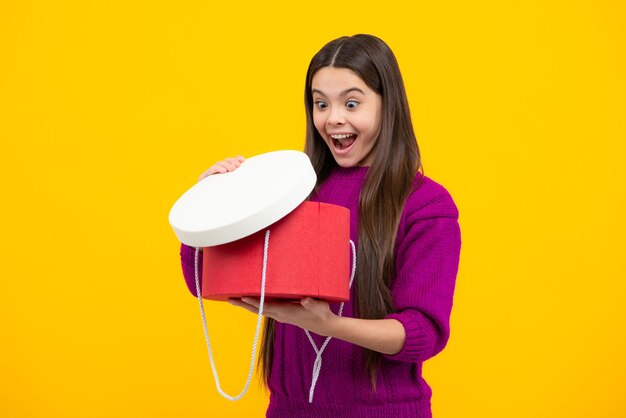 Excited face child teen girl 1214 years old with gift on yellow\
isolated background birthday holiday concept teenager hold present\
box amazed expression cheerful and glad