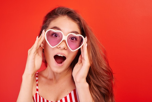 Excited face girl shopper surprised at the price in the store. Woman on a red background looks at a very good bargain