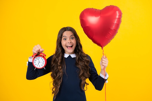 Excited face Punctual teen girl checking time Child with alarm clock showing time Amazed expression cheerful and glad