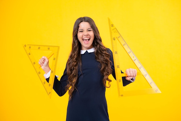 Excited face school girl holding measure for geometry lesson\
isolated on yellow background measuring equipment student study\
math amazed expression cheerful and glad