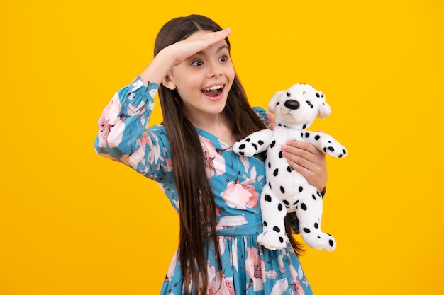 Excited face teen girl in casual clothes hold soft toy for birthday on yellow background kid spending time with her toys amazed expression cheerful and glad