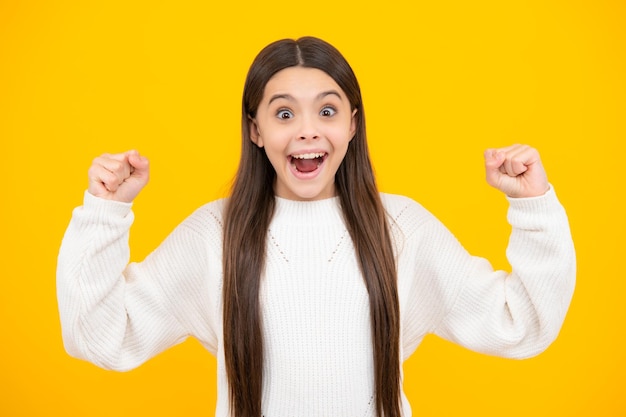 Excited face Teenager child girl rejoicing say yes looking happy and celebrating victory champion gesture fist pump on yellow background Amazed expression cheerful and glad