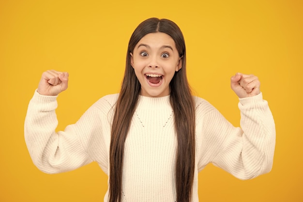 Excited face Teenager child girl rejoicing say yes looking happy and celebrating victory champion gesture fist pump on yellow background Amazed expression cheerful and glad