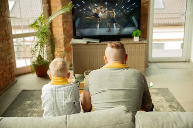 Excited family watching martial arts championship sport match at home Father and son