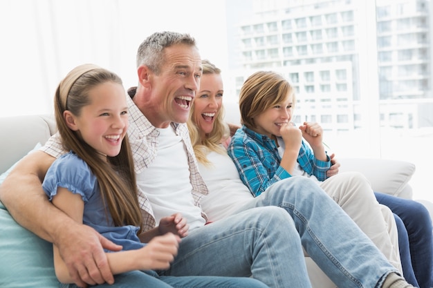 Excited family watching television on sofa