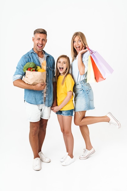 excited family woman and man with daughter holding food products and shopping bags isolated on white