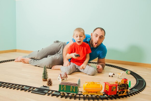 興奮した父と子がプレイルームで電車で遊んでいます