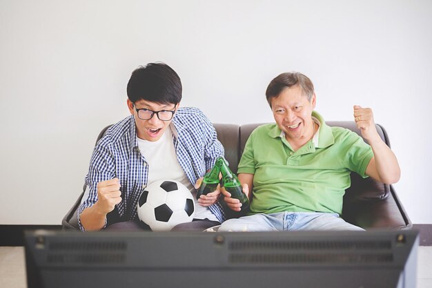 Photo excited father and son watching tv at home