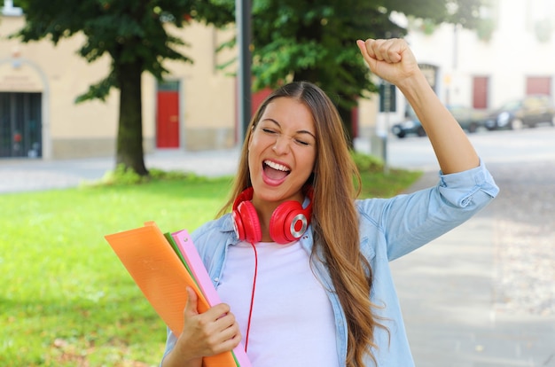 Excited female student holding notebooks