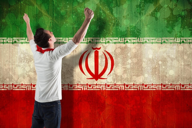 Foto appassionato di calcio eccitato che tifa contro la bandiera dell'iran in effetto grunge