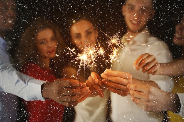 Excited friends holding bengal lights at New Year party, closeup