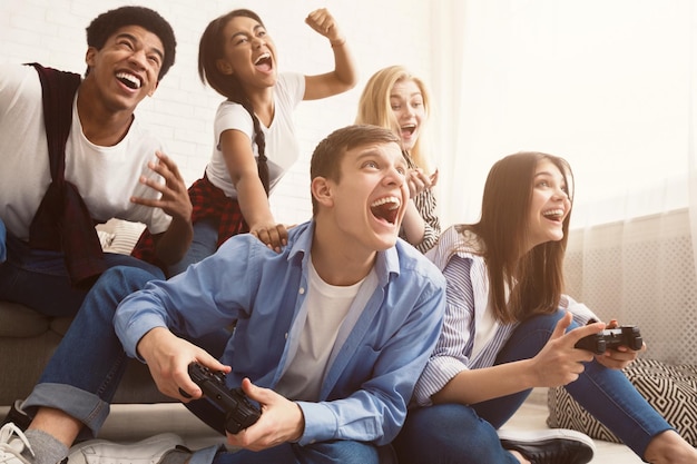 Excited friends playing video games at home