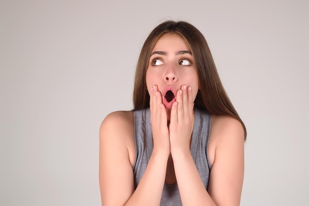 Excited fun young woman with surprised open mouth on studio background amazed astonished portrait of