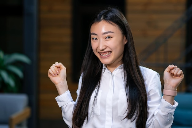 Photo excited funny young asian business woman celebrating success happy winner feeling overjoyed