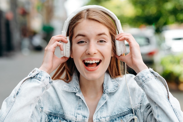 Excited girl  in an earphones outdoor screaming with a wide open mouth  