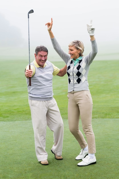 Excited golfing couple cheering