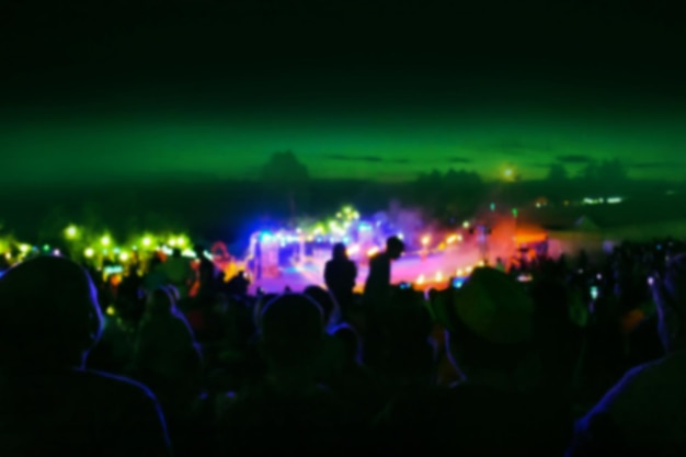 Excited guests up the front at night music festival trendy\
festival blurred bokeh texture during summer night