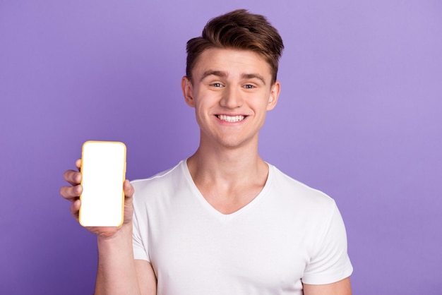 Excited guy in casual wear hold cellphone with empty screen on bright studio background space for website