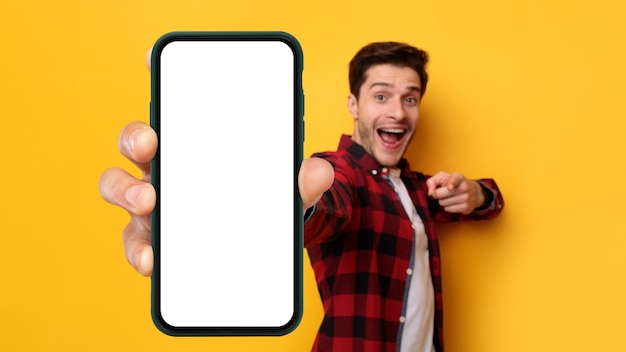 Ragazzo eccitato che punta allo schermo bianco dello smartphone vuoto