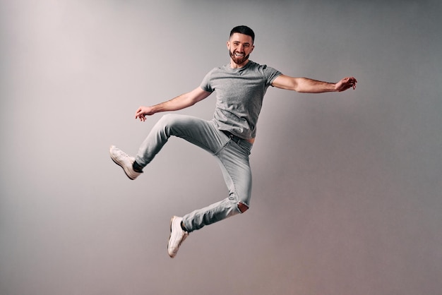 excited handsome young man in gray tshirt jumping while celebrating success isolated gray background