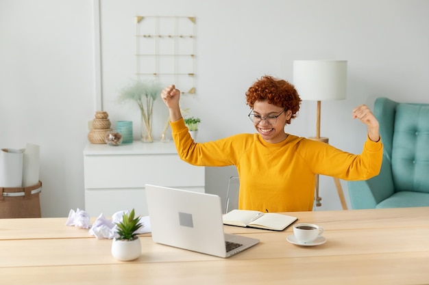 Excited happy african american woman euphoric winner girl student looking at laptop passed exam read