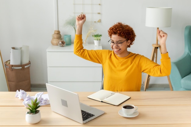 Excited happy african american woman winner Girl female student looking at laptop passed exam reading great news getting good result winning online bid feeling amazed looking at computer at home