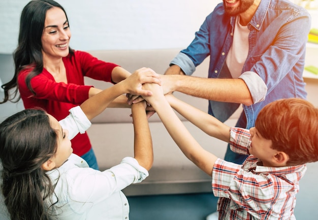 Excited and happy beautiful family team holding together hands are smiling and shouting during some game process at home