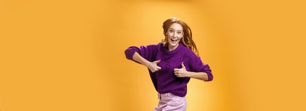 Excited and happy funny young redhead female in purple sweater jumping from happiness and person