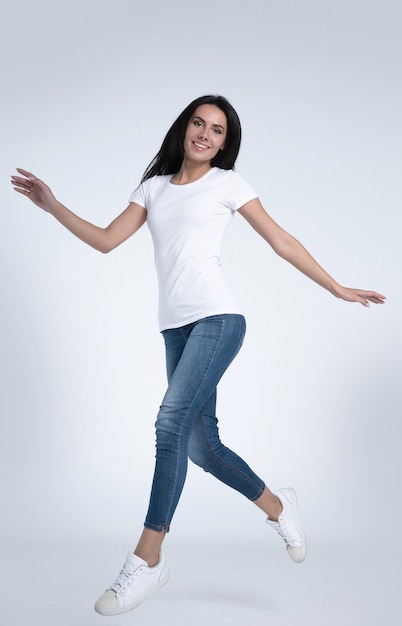 Excited and happy gorgeous woman is jumping and shouting in white t-shirts and jeans isolated on white background.