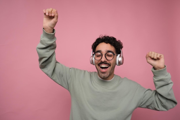 excited and happy guy in headphones with his hands raised up