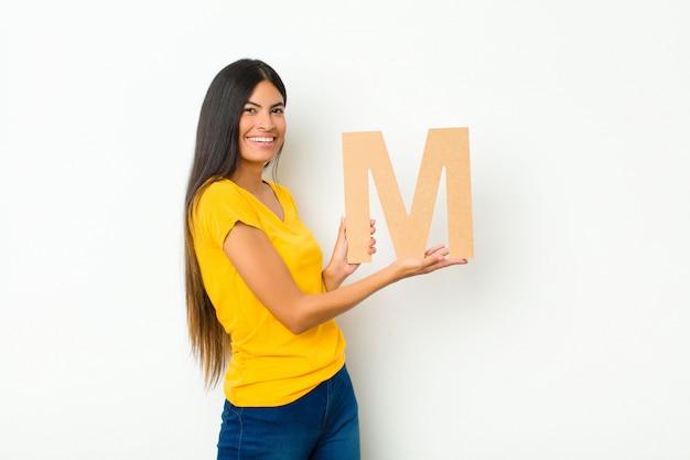 excited, happy, joyful, holding the letter M of the alphabet to form a word or a sentence.