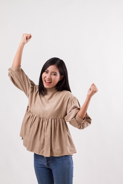 Взволнованная счастливая улыбающаяся умная повседневная азиатская женщина позирует в веселой, успешной позе