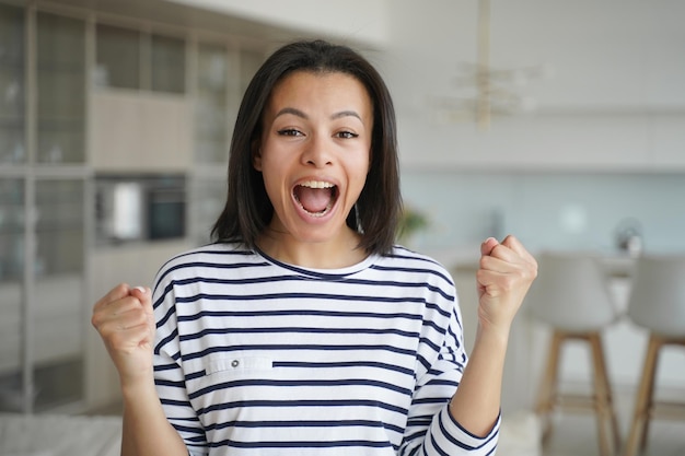 Excited happy woman makes yes gesture celebrates relocation at new house achievement success