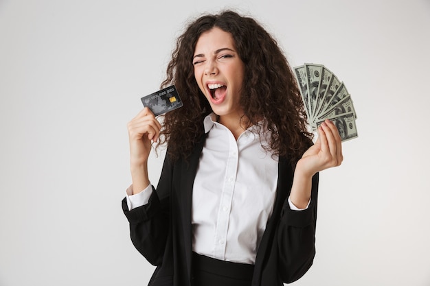 Возбужденная счастливая молодая бизнес-леди с кредитной картой и деньгами.
