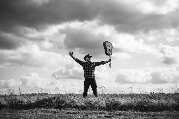 Excited hiker man with guitar looking at beautiful view man hipster hiker in autumn field