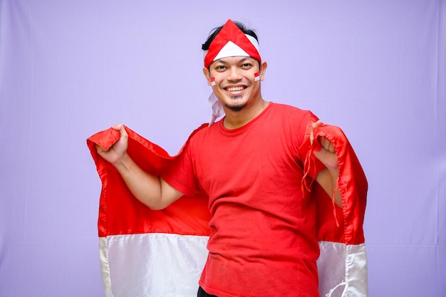 Excited indonesian man celebrate indonesian independence day on 17 august holding indonesian flag