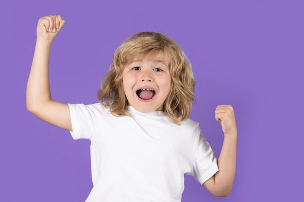 Excited kid boy celebrating victory on studio isolated background surprised kids face amazed