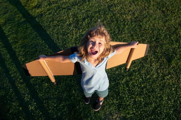 Excited kid with backpack wings child playing pilot aviator and dreams outdoors in park smiling kid ...