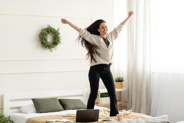 Excited lady listening to music and dancing at home