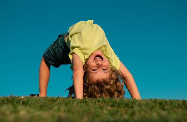 Photo excited little boy laying on the grass in the park outdoor portrait of pretty little boy on fresh