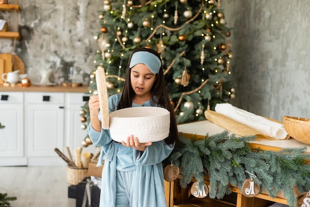 Excited little girl opening christmas present in front of the fir tree